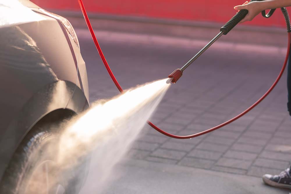 Χρήστης πλένει αυτοκίνητο με πλυστικό μηχάνημα σε εξωτερικό χώρο